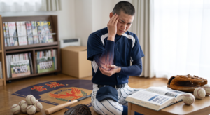 野球部の学生が肘の痛みを訴える様子