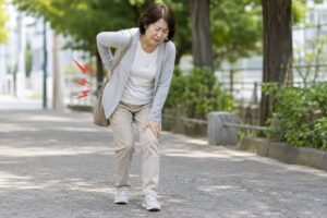 腰椎すべり症による腰の痛みを感じながら歩く女性のイメージ